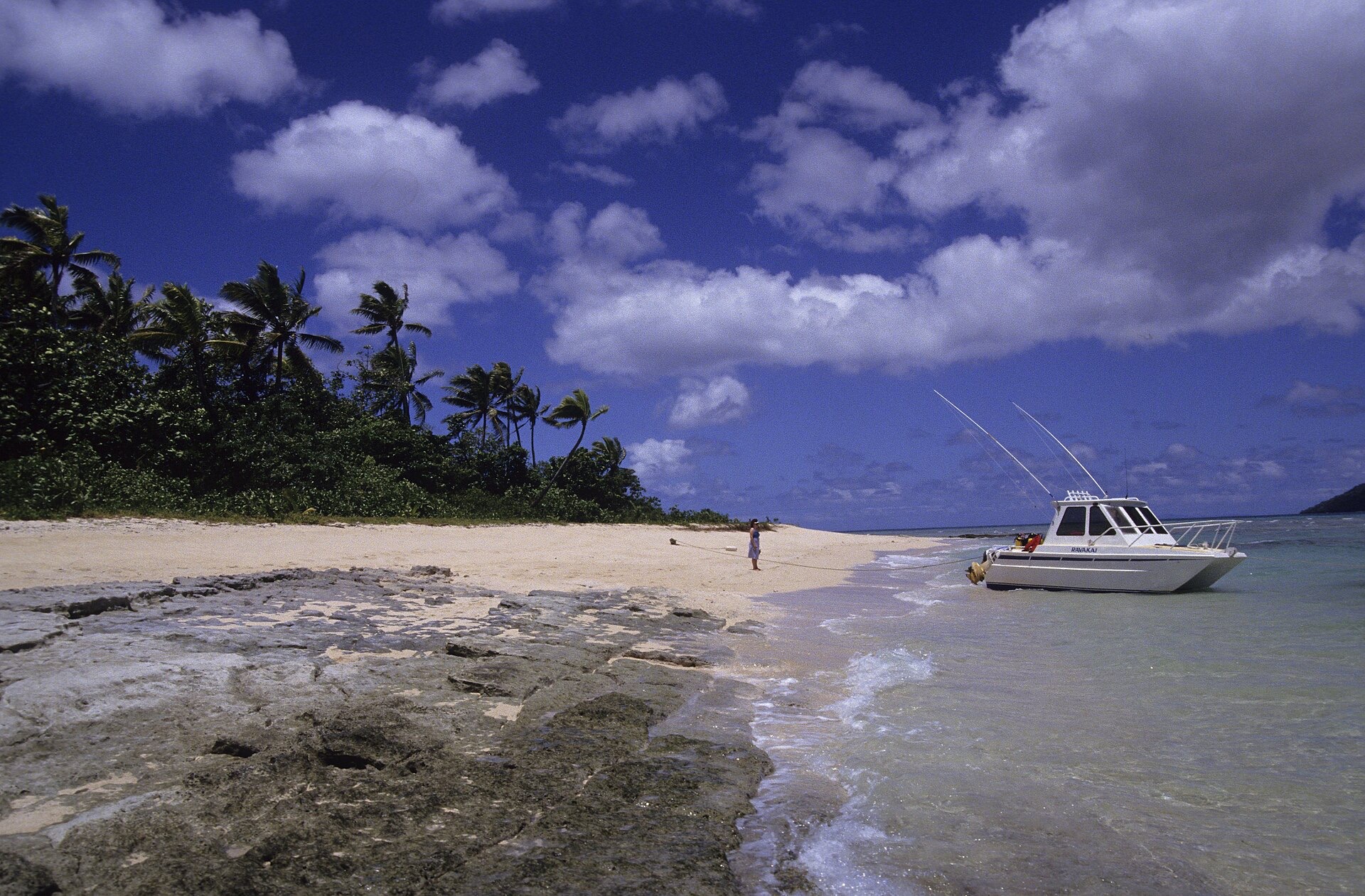 Beach on Taveuni, Fiji, with a small boat pulled up on the sand and heavy clouds building over the sea